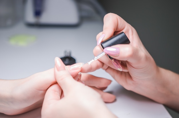 Manicurist master makes manicure on woman's hand