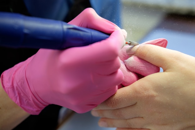 Manicurist polishing nails using polish machine