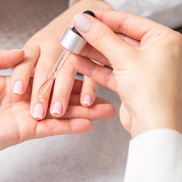 Manicurist pours oil on nails of woman