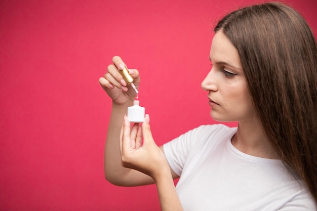 Manicurist showing nail polish, pink background.