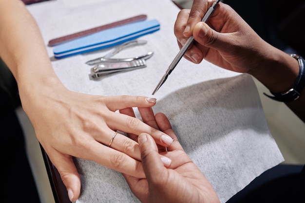 Manicurist using cuticle pusher