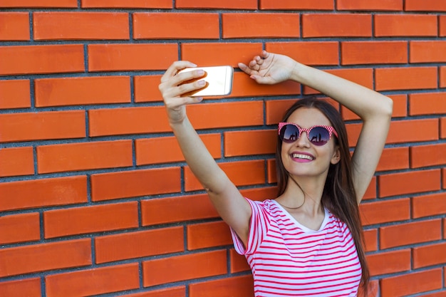 Manier vrij glimlachend jong meisje die beeld zelfportret op smartphone nemen