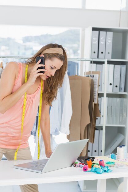 Foto manierontwerper die laptop en cellphone in studio met behulp van