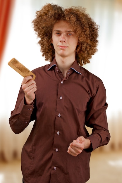 manin a brown shirt on uses a wooden comb