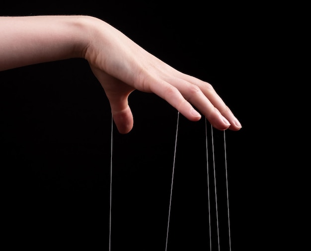 Photo manipulation abuse concept female hand pulling strings on black background