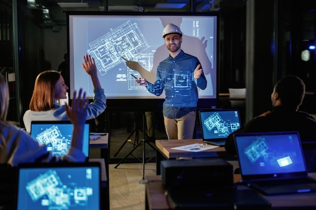 Manlijke architect toont bouwplaatsproject op blauwe projector voor mensen