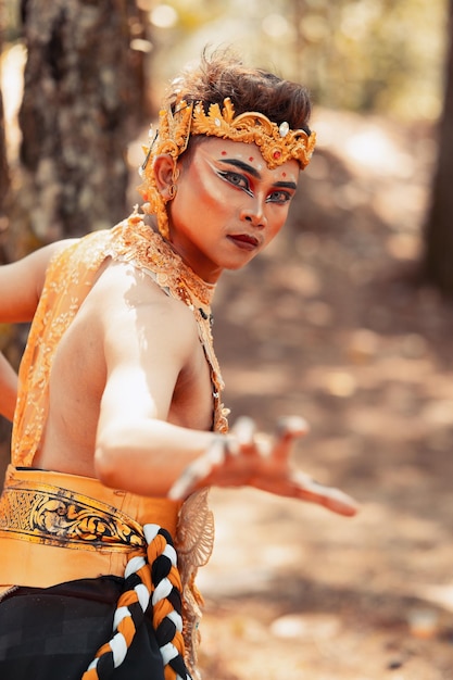 Manly Asian man posing in a golden crown and golden clothes while wearing makeup