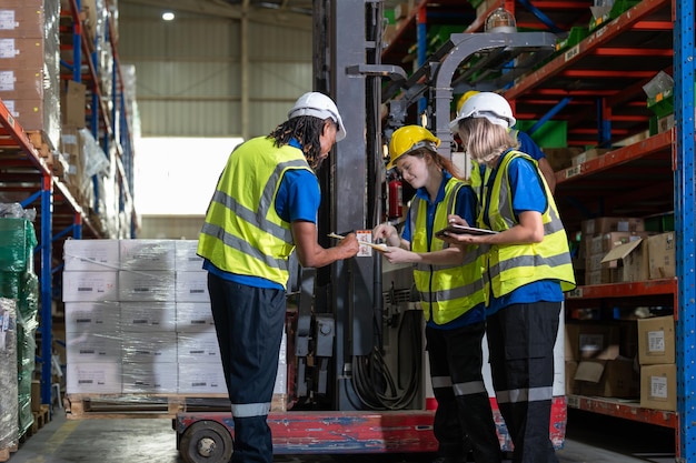 Mannelijk en vrouwelijk team van magazijnwerkers bespreken en bereiden het verplaatsen van het product naar de plank met een heftruck voor