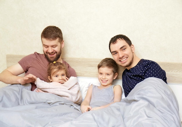 Mannelijk homopaar met kinderen die thuis in bed rusten