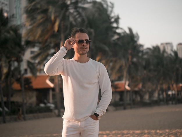 Mannelijk model in witte kleren op het strand