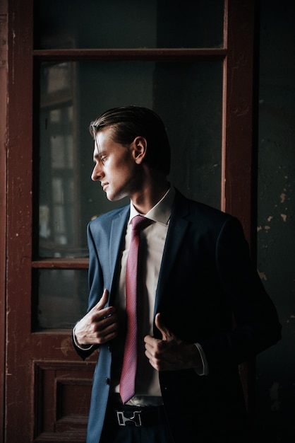 Mannelijk model in zwart pak en rode stropdas vormt voor reclame voor herenkleding. Schieten voor herenkledingwinkel