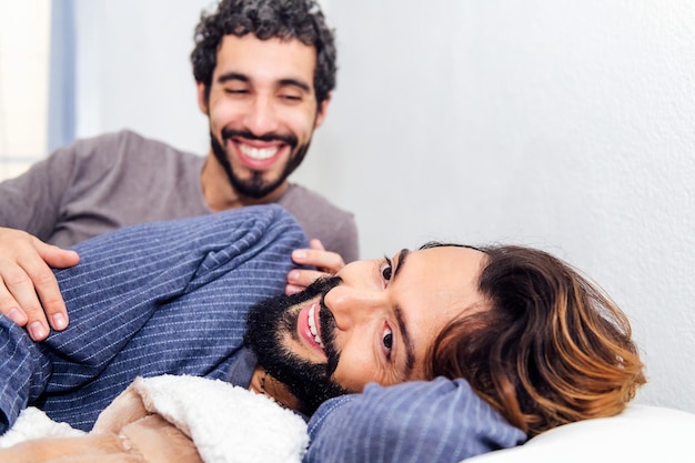 Mannelijk paar ontspannen in bed en gelukkig glimlachen