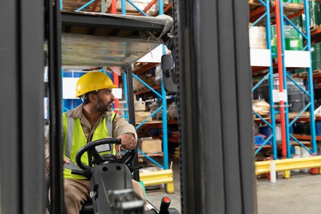 Foto mannelijk personeel dat vorkheftrucks rijdt in een magazijn