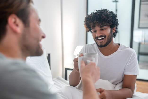 Mannelijk stel dat in bed blijft en koffie drinkt