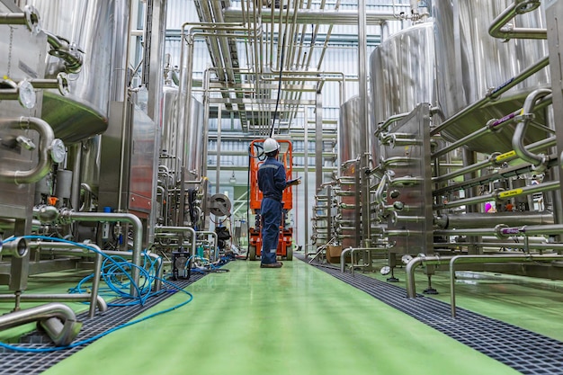 Mannelijk werk visuele inspectie van roestvrijstalen tanks en in de uitrusting tankfaciliteit voor bier dranken kelder bij de met verticale roestvrije