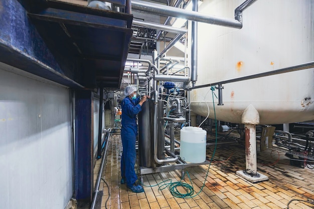 Foto mannelijk werkinspectieproces roestvrijstalen tanks en pijp met drukmeter in apparatuurtankfaciliteit voor waterkelder bij de met verticale roestvrijstalen mengtank