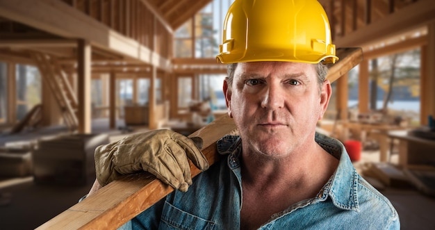 Foto mannelijke aannemer op een bouwplaats met een helm en werkhandschoenen die hout vasthoudt 2x4 xa