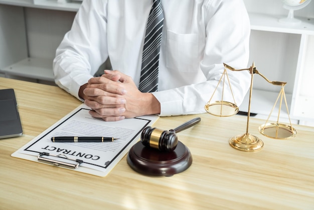 Foto mannelijke advocaat of jurist die werkt met papieren procesdocumenten van het landgoedrechtszaak wetboeken en houten hamer op tafel in kantoor