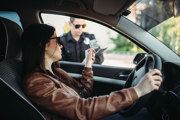 Mannelijke agent in uniform schrijft een boete uit aan vrouwelijke chauffeur