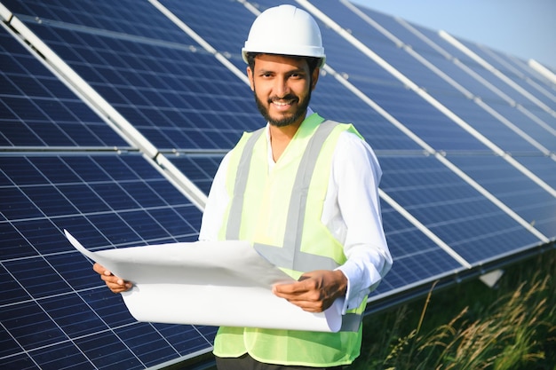 Mannelijke Arabische ingenieur die op het veld staat met rijen zonnepanelen