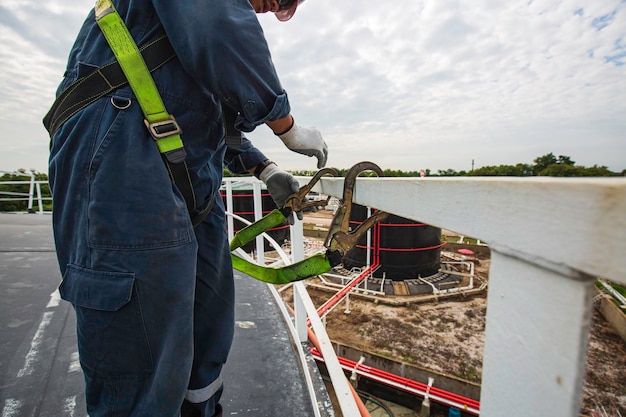 Mannelijke arbeider die veiligheidsharnas draagt en alleen veiligheid werkt bij hoge leuning