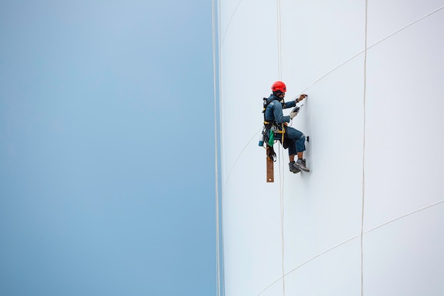 Mannelijke arbeiders beneden in hoogte tank touwtoegang inspectie van dikte schaalplaat opslagtank gas propaan veiligheidswerk op hoogte.