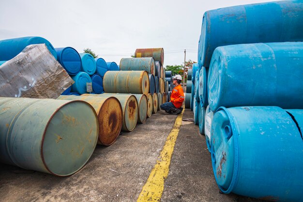 Mannelijke arbeidersinspectie registreert oude vaten olievoorraad blauw en groen horizontaal of chemisch voor in de industrie.