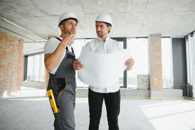 Mannelijke architect die instructies geeft aan zijn voorman op de bouwplaats