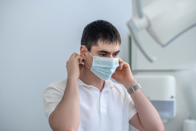 Mannelijke arts. Jonge mannelijke arts die een beschermend masker opzet