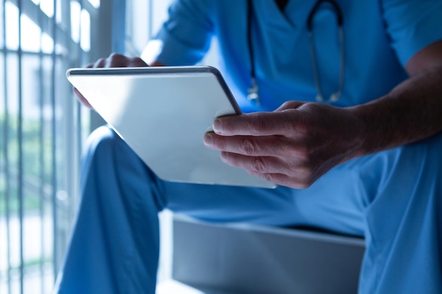 Mannelijke arts met een digitale tablet op de trap in het ziekenhuis