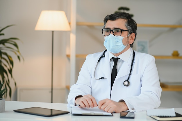 Mannelijke arts met medisch gezichtsmasker en een stethoscoop bij kliniek