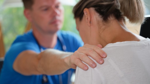 Foto mannelijke arts ondersteunt trieste vrouwelijke patiënt in kliniek kantoor mannelijke arts raakt schouder overstuur