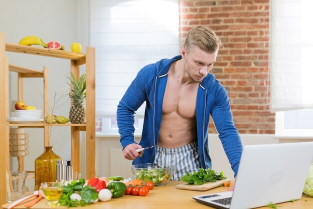 Mannelijke atleet bereiden van gezonde voeding thuis in de keuken, online studeren