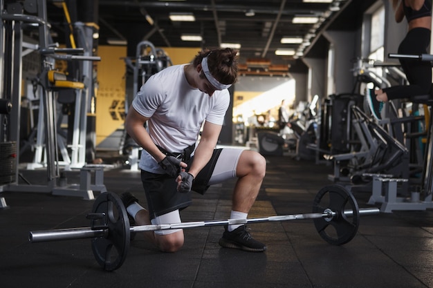 Mannelijke atleet die zich voorbereidt op een haltertraining met een gewichthefriem