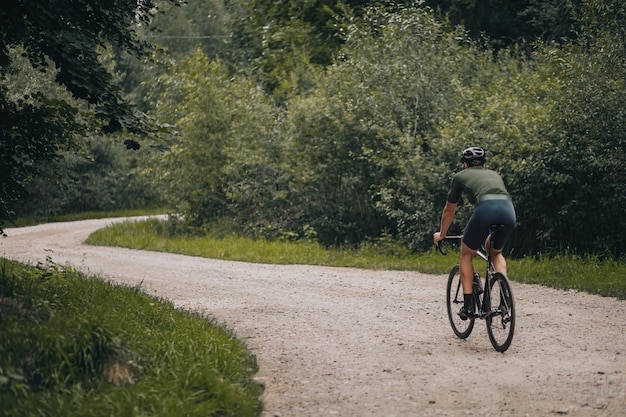 Mannelijke atleet rijdt terug op pad in groen bos