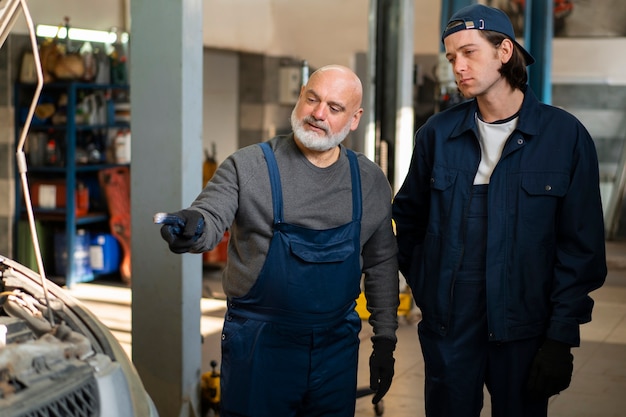 Mannelijke automonteur die werkt in de autoreparatiewerkplaats