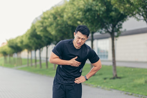 Mannelijke aziatische atleet, heeft pijn op de borst, fitness in het park en hardlopen, hartpijn na cardio-oefening