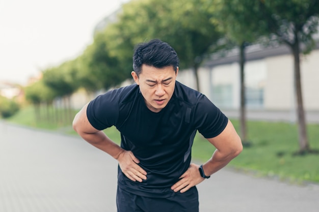 Mannelijke Aziatische atleet met buikpijn na fitness in park