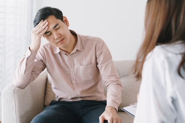 Mannelijke Aziatische patiënt met het onderzoek van psycholoogvrouwen het raadplegen