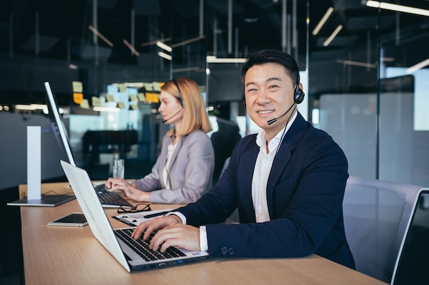 Mannelijke aziatische zakenman gebruikt headset voor videocommunicatie zakenman die naar de camera kijkt en glimlacht