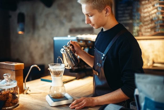 Foto mannelijke barista giet gemalen koffie in het glas