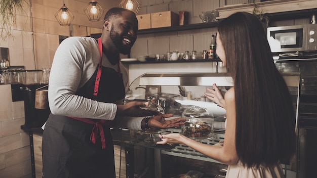 Mannelijke barista helpt een meisje om een dessert te kiezen