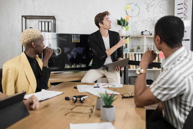 Foto mannelijke bedrijfsmedewerker in formele kleding die aan een bureau zit en luistert naar de teamleider