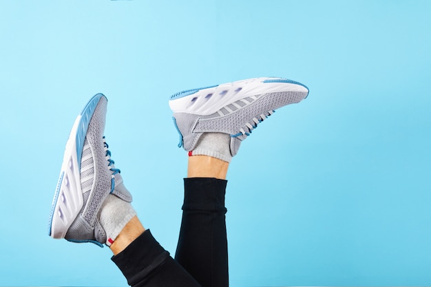 Mannelijke benen die sneakers dragen over blauwe muur. Sportschoenen voor training in de sportschool. Man in het runnen van sneakers in de buurt van kleur muur. detailopname