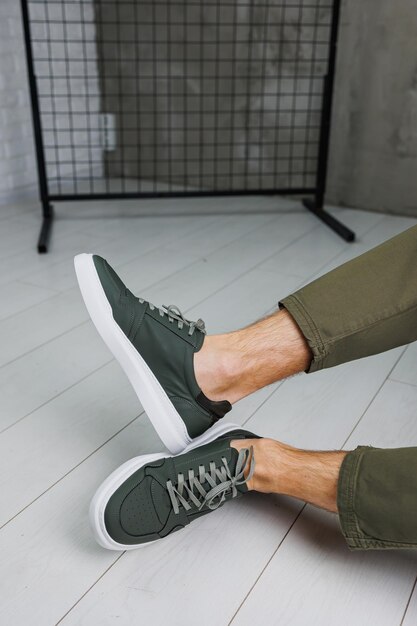 Mannelijke benen in broek en groene casual sneakers Modieuze herenschoenen