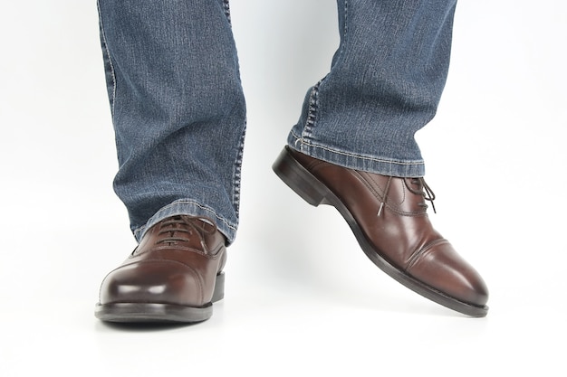 Mannelijke benen in jeans en bruine klassieke schoenen op witte achtergrond