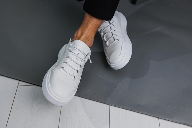 Mannelijke benen in zwarte broek en witte casual sneakers Modieuze herenschoenen