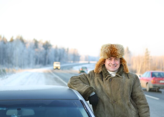 Mannelijke bestuurder van de auto op de achtergrond van een winterse lucht