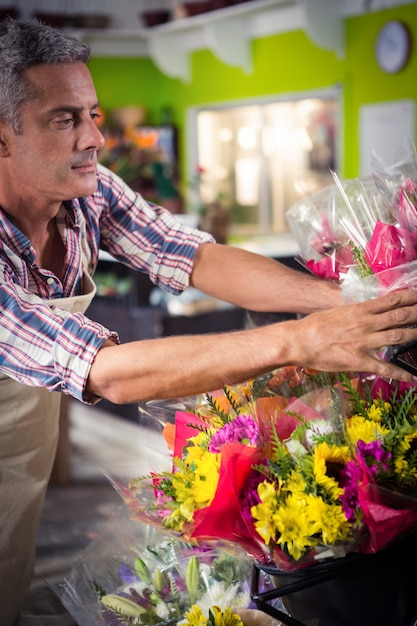 Mannelijke bloemist die boeket van bloem schikt