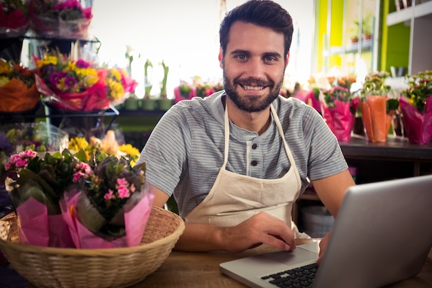 Mannelijke bloemist die laptop met behulp van bij zijn bloemwinkel